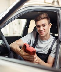 Junger Mitarbeiter mit Diagnosegerät im Fahrzeug