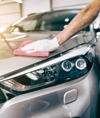 Car detailing - the man holds the microfiber in hand and polishes the car. Selective focus.