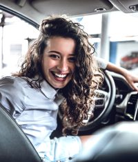 Portrait of beautiful happy young woman inside in new car.