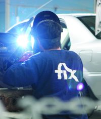 Ein Karosseriebauer mit Fix Auto-Pullover schweißt an einem Fahrzeug