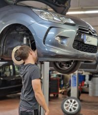 Ein Mitarbeiter von Fix Auto Solms führt Reparaturen an einem Fahrzeug auf der Hebebühne durch.