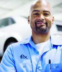 Portrait of an auto body technician wearing a shop uniform standing in a repair facility